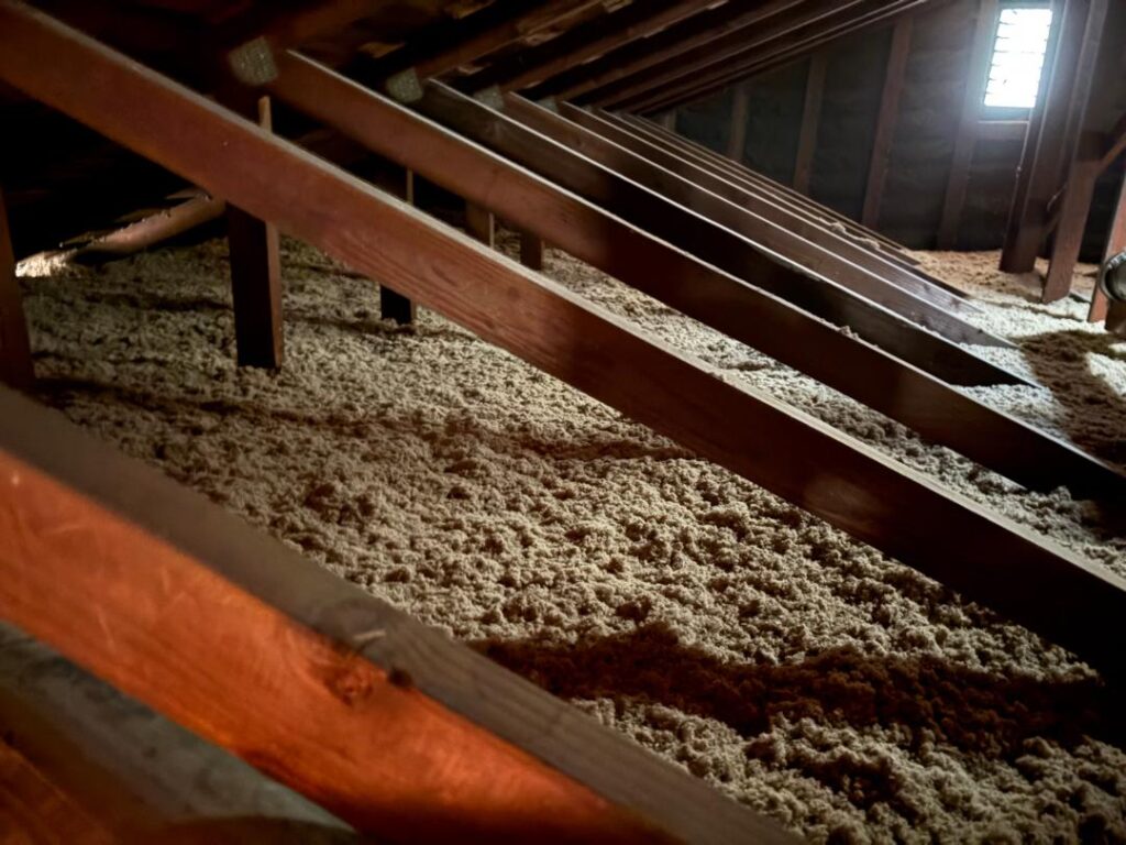 Attic insulation, showing cellulose insulation packed between wooden joists.