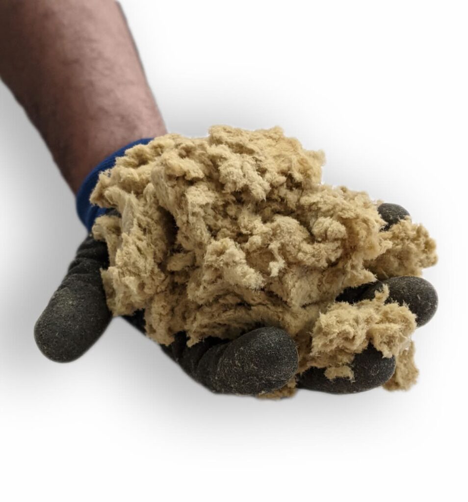 Hand in glove holding loose-fill cellulose attic insulation